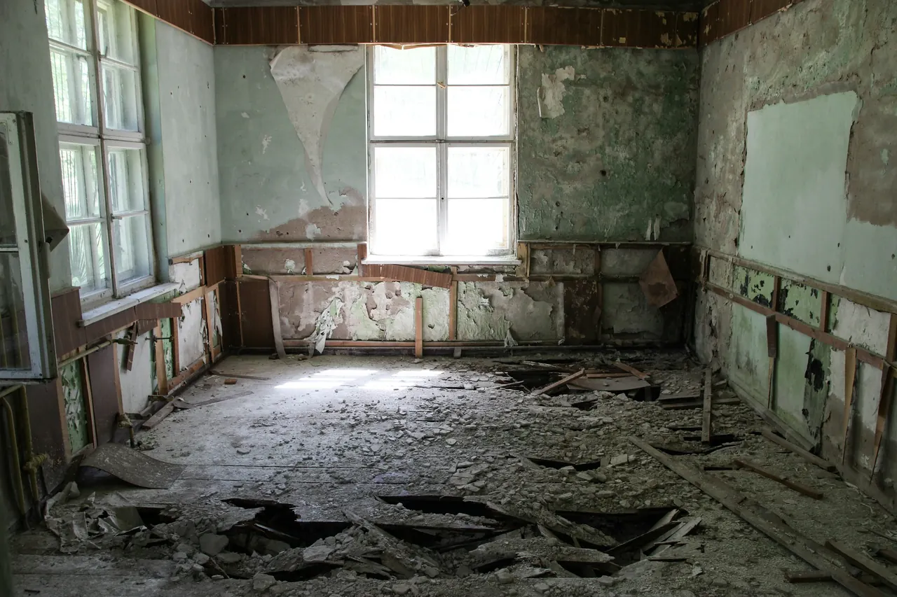 Habitación en ruina con el suelo levantado y las paredes desconchadas