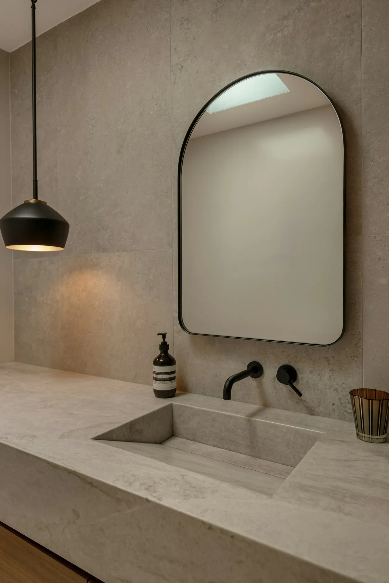 Baño de piedra con lavabo tallado y espejo en arco