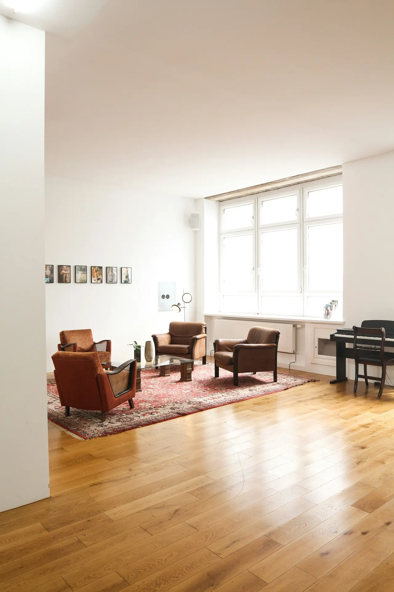 Salón de techos altos con suelo de roble, butacas de cuero y grandes ventanas