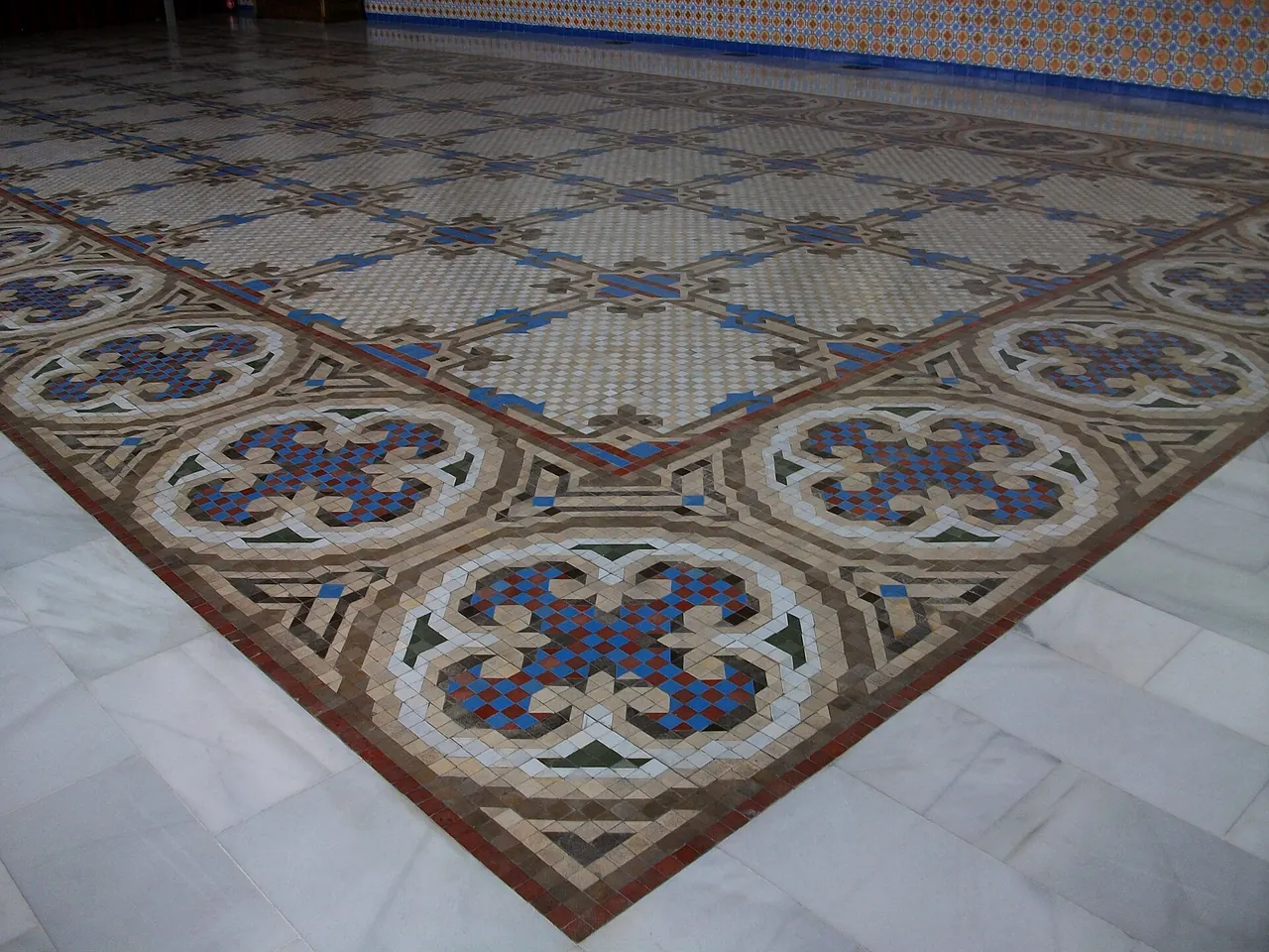 Suelo de mosaico Nolla con rosetones azules y una cenefa en el salón del Palau de l’Exposició de Valencia